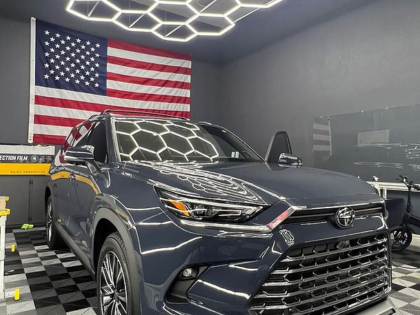 Dark grey SUV under panel lights after ceramic work